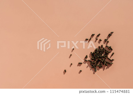 Scattered green and wet nasvay granules on a brown background Scattered green and wet nasvay granules on a brown background 115474881