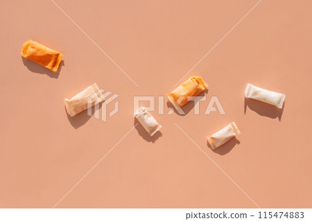 Snus sachets with different flavors on an orange background 115474883