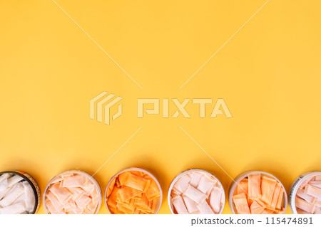 Multi-colored snus bags with different flavors are arranged in jars in a row on a yellow background Multi-colored snus bags with different flavors are arranged in jars in a row on a yellow background 115474891