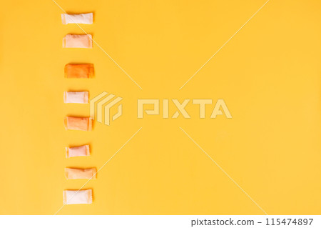 Multi-colored and different-flavored snus bags on a yellow background Multi-colored and different-flavored snus bags on a yellow background 115474897