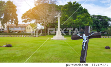 A red wooden cross on a blurred cemetery background. A red wooden cross on a blurred cemetery background. 115475637