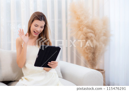 Young asian woman sitting on sofa using digital tablet computer for video call in living room. Young asian woman sitting on sofa using digital tablet computer for video call in living room. 115476291