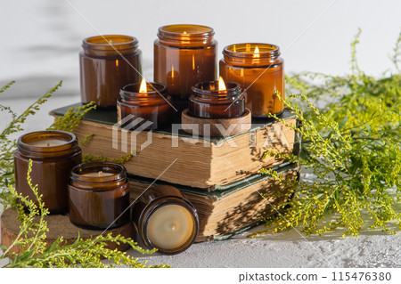 A set of different aroma candles in brown glass jars. Scented handmade candle. Soy candles are burning in a jar. Aromatherapy and relax in spa and home. Still life. Fire in brown jar 115476380