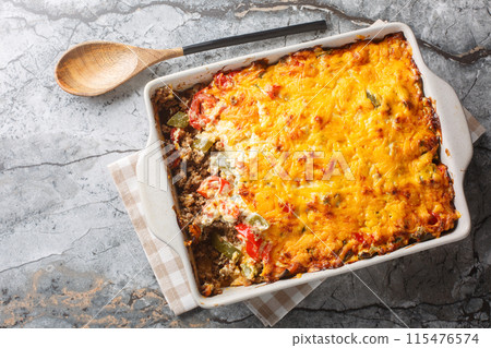 John Wayne Casserole is a delicious and filling layered casserole with taco meat, buttery biscuits, vegetables and a cheesy topping closeup on the baking dish. Horizontal top view John Wayne Casserole is a delicious and filling layered casserole with taco meat, buttery biscuits, vegetables and a cheesy topping closeup on the baking dish. Horizontal top view 115476574
