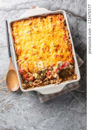 Delicious John Wayne casserole with beef, biscuits, cheese and vegetables close-up in a baking dish. Vertical top view 115476577