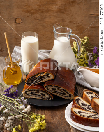 Roll with poppy seeds and a glass of milk. Food on the table. Sweet pastries. Homemade simple yeast bun with filling. Breakfast on a wooden table. lactose and gluten. Roll with poppy seeds and a glass of milk. Food on the table. Sweet pastries. Homemade simple yeast bun with filling. Breakfast on a wooden table. lactose and gluten. 115477166