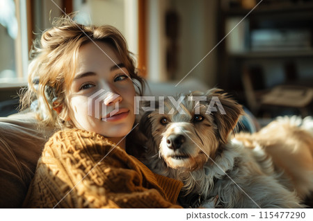 Caucasian woman is sitting on the sofa with her dog in the living room. 115477290