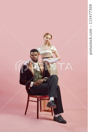 Classical noble portrait of regal gentleman in rich velvet coat, with lady standing confidently behind him against pink studio background Classical noble portrait of regal gentleman in rich velvet coat, with lady standing confidently behind him against pink studio background 115477309