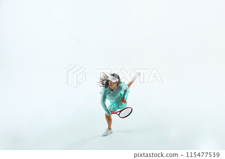 Overhead perspective of athletic woman, tennis player in teal sportswear training in motion against white studio background. Overhead perspective of athletic woman, tennis player in teal sportswear training in motion against white studio background. 115477539