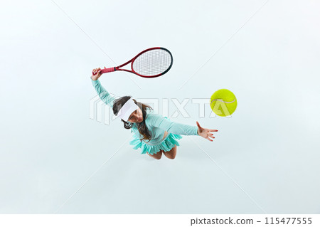 Aerial view of female tennis player, sportsman in mid-action, serving ball against white studio background. 115477555