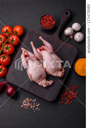Whole raw quails with salt, spices and herbs on a dark concrete background Whole raw quails with salt, spices and herbs on a dark concrete background 115478980