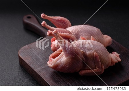 Whole raw quails with salt, spices and herbs on a dark concrete background 115478983