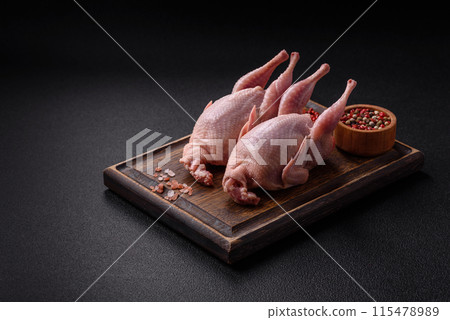 Whole raw quails with salt, spices and herbs on a dark concrete background Whole raw quails with salt, spices and herbs on a dark concrete background 115478989
