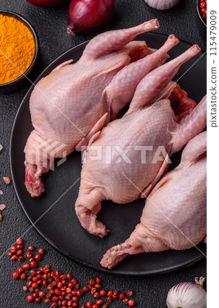 Whole raw quails with salt, spices and herbs on a dark concrete background Whole raw quails with salt, spices and herbs on a dark concrete background 115479009