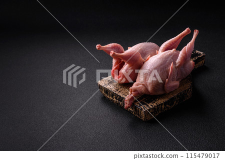 Whole raw quails with salt, spices and herbs on a dark concrete background Whole raw quails with salt, spices and herbs on a dark concrete background 115479017