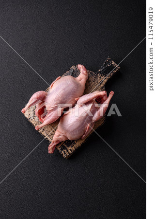 Whole raw quails with salt, spices and herbs on a dark concrete background Whole raw quails with salt, spices and herbs on a dark concrete background 115479019