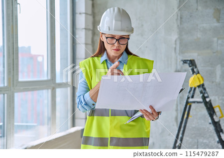 Technical profession woman in protective vest helmet working on construction 115479287