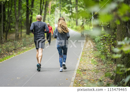 Couple is running down in a park with lush greenery, training, jogging 115479465