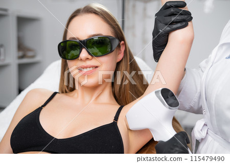 A woman receives laser epilation treatment on her underarm. 115479490