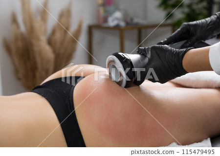 A masseur performs correction on the buttocks with the help of ultrasonic cavitation A masseur performs correction on the buttocks with the help of ultrasonic cavitation 115479495