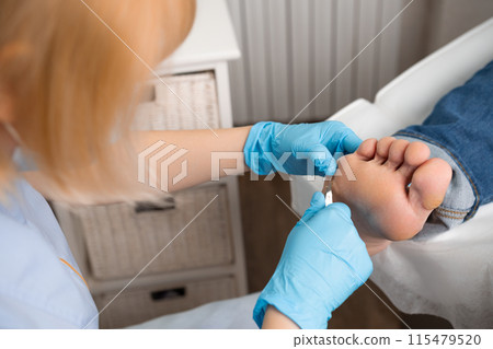Podiatrist performs callus removal using clippers on a womans foot at the medical center. Podiatrist performs callus removal using clippers on a womans foot at the medical center. 115479520