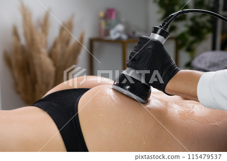 Close up womans buttocks during the procedure of ultrasound cavitation for body contouring at beauty salon Close up womans buttocks during the procedure of ultrasound cavitation for body contouring at beauty salon 115479537
