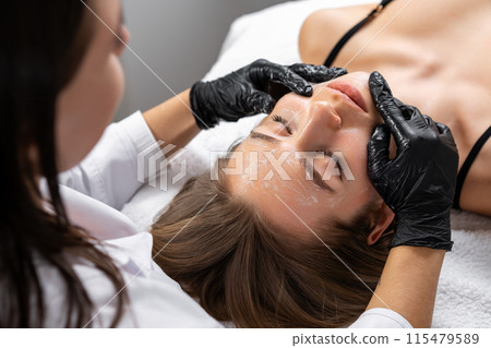 Specialist shows skillful manipulation of client facial contours. Spa worker ensures personalized treatment addressing individual needs Specialist shows skillful manipulation of client facial contours. Spa worker ensures personalized treatment addressing individual needs 115479589