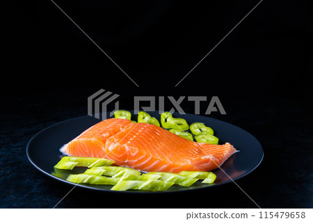 Salted fish salmon with pepper and onions on a black plate. Top view. Free space for your text. Salted fish salmon with pepper and onions on a black plate. Top view. Free space for your text. 115479658