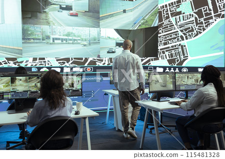 Middle eastern manager overseeing his staff order tracking activity, instructing operators to update customers on parcel shipment progress. Delivery agency monitoring their trucks in traffic. Middle eastern manager overseeing his staff order tracking activity, instructing operators to update customers on parcel shipment progress. Delivery agency monitoring their trucks in traffic. 115481328