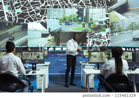 African american manager overseeing monitoring activity in control center, shipping agency ensuring express shipment on all orders. Employees operators guiding couriers in traffic. African american manager overseeing monitoring activity in control center, shipping agency ensuring express shipment on all orders. Employees operators guiding couriers in traffic. 115481329