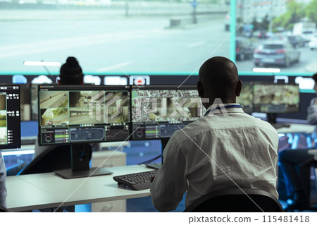Observation room employee reviewing video surveillance footage to find illegal activity within urban traffic, big screen. African american man collecting data via CCTV radar system. 115481418