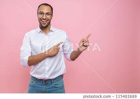 Happy cheerful man in white shirt pointing at empty space for promotion 115481689
