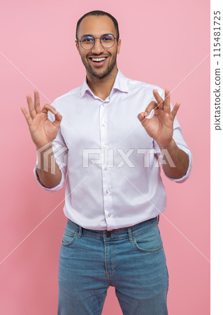 Satisfied man in white shirt showing okay gesture Satisfied man in white shirt showing okay gesture 115481725