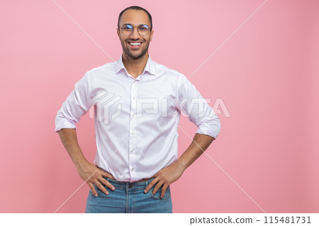 Confident smiling man in white shirt standing with hands on hips 115481731
