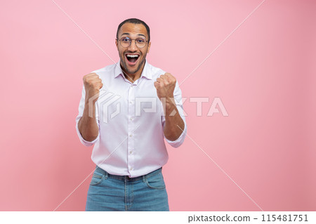 Overjoyed man in white shirt celebrating success with clenched fists 115481751