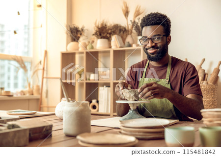 African american young man working with clay in pottery studio African american young man working with clay in pottery studio 115481842