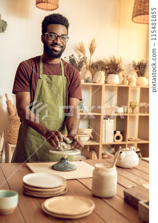Dark-skinned sculptor molding clay in his hands Dark-skinned sculptor molding clay in his hands 115481855