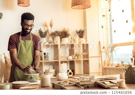 Dark-skinned sculptor molding clay in his hands Dark-skinned sculptor molding clay in his hands 115481856