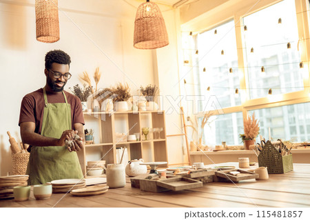 Dark-skinned sculptor molding clay in his hands Dark-skinned sculptor molding clay in his hands 115481857