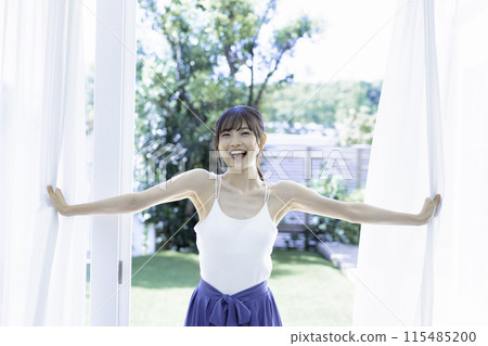 Active young woman opening lace curtains 115485200