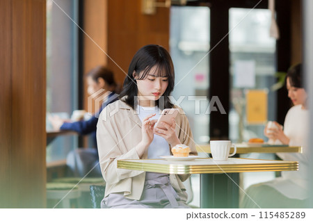 A young woman operating a smartphone in a cafe 115485289