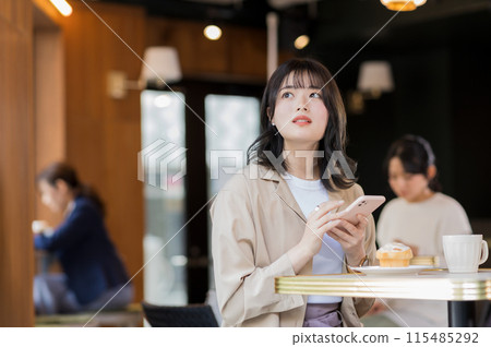 A young woman operating a smartphone in a cafe 115485292
