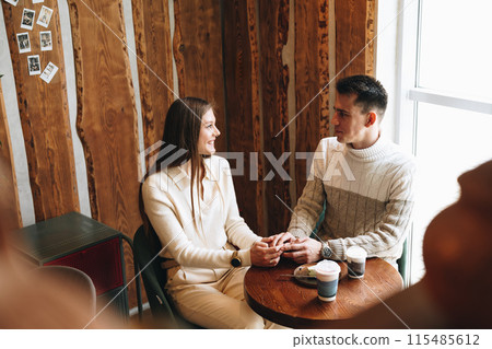 Two People Engaged in Casual Conversation at a Cozy Cafe During the Day Two People Engaged in Casual Conversation at a Cozy Cafe During the Day 115485612