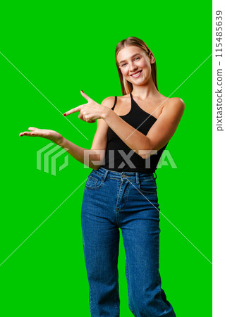 Young Woman Pointing at Something against green background 115485639