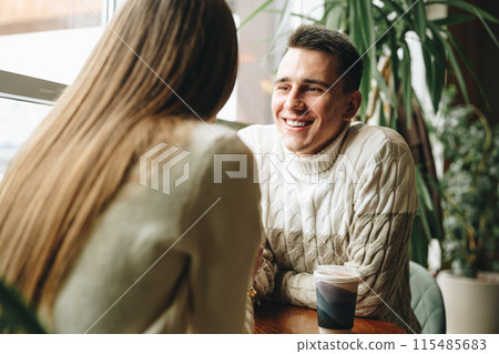 Smiling Man Engaged in a Casual Conversation at a Cozy Cafe During Daytime 115485683