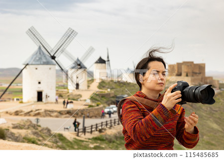 Woman tourist with a camera Consuegra photographs the surroundings 115485685