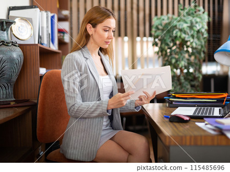 Attentive business woman studies important documents in the office 115485696
