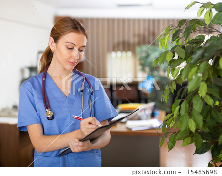 Nurse standing in hall with clipboard in hands 115485698