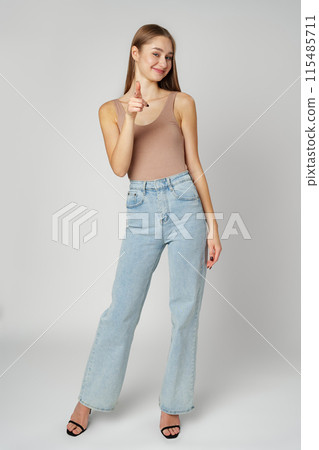 Young Woman Pointing Towards Camera With a Playful Expression in a Studio 115485711