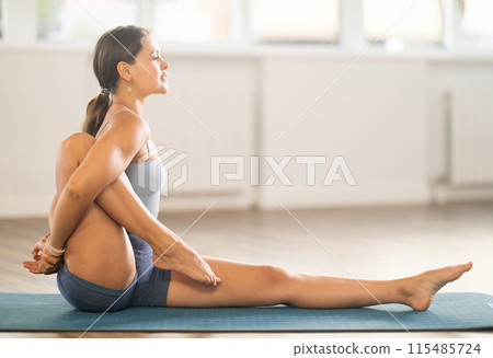 Sporty girl performing powerful dynamic yoga asanas in studio Sporty girl performing powerful dynamic yoga asanas in studio 115485724